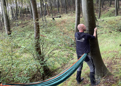 En lærer fra Fonden Ørtings specialskole for børn og unge med autisme er ved at hænge en hængekøje op i skoven