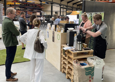 To elever fra Fonden Ørting står i vores kaffebar og er i gang med at lave barista-kaffe til to gæster.